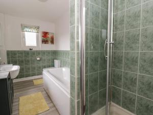 a bathroom with a shower and a tub and a sink at Glanyrafon Smithy in Llandysul +20 photos