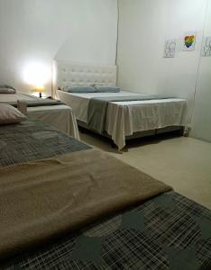 a bedroom with two beds and a table with a lamp at Posada Dale Dale in São Gabriel
