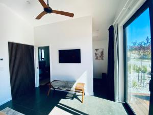 a living room with a ceiling fan and a chair at The Modern Alpine Oasis - Mountain Views - Rainfall Shower - Perfect for Couples in Wanaka