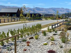 a road with a fence and plants on the side at The Modern Alpine Oasis - Mountain Views - Rainfall Shower - Perfect for Couples in Wanaka
