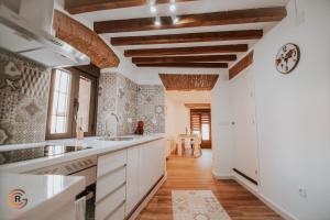 a kitchen with white cabinets and wooden ceilings at Apartamentos Cañón de la Rinconada in Trujillo