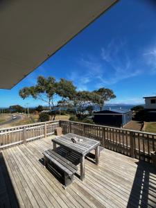 a picnic table on a deck with a view of the ocean at Bruny Seaview Escape in Alonnah