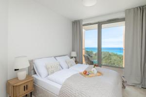 a white bedroom with a bed and a large window at Apartment with direct sea view in Pobierowo +37 photos