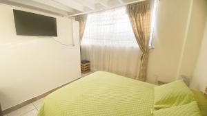 a bedroom with a bed and a window with a television at SUITE AMOBLADA TODO INCLUIDO in Quito