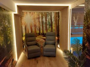 a room with two chairs and a painting of a forest at Landgasthaus Sonne in Freudenstadt