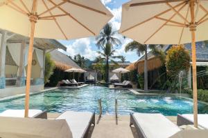 a pool at a resort with chairs and umbrellas at Rascals Hotel - Adults Only in Kuta Lombok