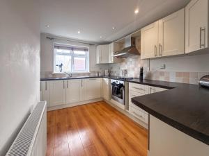 a kitchen with white cabinets and a wooden floor at Royal Retreat in Wisbech