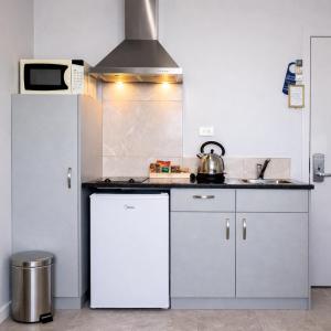 a kitchen with white cabinets and a white refrigerator at BKs Premier Motel Esplanade in Lower Hutt