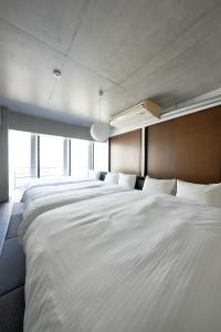 a row of white beds in a room at ARTK'SJosui in Fukuoka