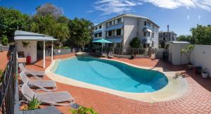a swimming pool with chairs and a house at Whalewatch Ocean Beach Resort in Point Lookout