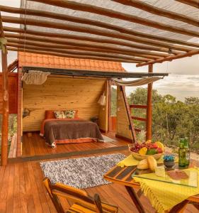 a wooden deck with a bed and a table at Glampiri in Pirenópolis