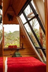 a bedroom with a large window in a cabin at Glampiri in Pirenópolis