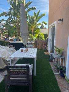 a white picnic table and an umbrella on a lawn at Eastside Costa Mesa Residence in Costa Mesa