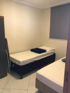 two beds in a small room with a window at Apto completo próximo a Johnson e Johnson e Dutra in São José dos Campos