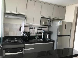 a kitchen with white cabinets and a sink and a refrigerator at Apto completo próximo a Johnson e Johnson e Dutra in São José dos Campos