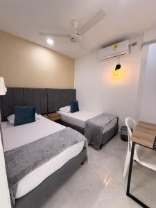 a bedroom with two beds and a table and a desk at Casa Calina Hotel in Caucasia
