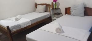 a room with two beds with white sheets at Hostal La Cascada San Ramón in Mérida