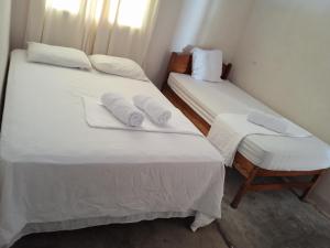 two beds in a room with white sheets and pillows at Hostal La Cascada San Ramón in Mérida +80 photos