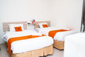 three beds in a room with white walls at L'cost Homestay in Sawah +16 photos