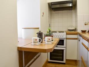 two coffee mugs sitting on a wooden counter in a kitchen at Spey Cottage in Aberlour
