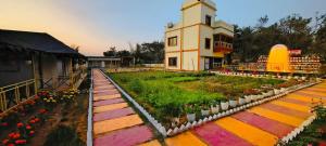 a building with a clock tower and a garden with flowers at Palashbhumi Resort in Barhanti