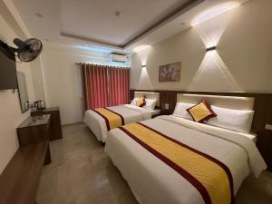 a hotel room with two beds and a television at Marina Cua Lo Hotel in Cửa Lô