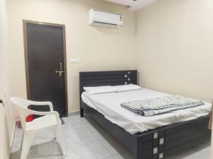a bedroom with a bed and a chair and a door at Sri RENUKA VSR Residency in Avanigadda
