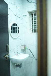 a white bathroom with a sink and a mirror at Sri RENUKA VSR Residency in Avanigadda +4 photos