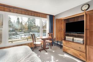 a bedroom with a large window and a table and a tv at Riverfront Studio with Trail access in Bend