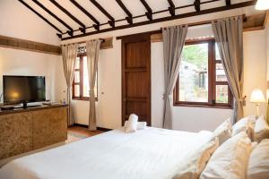 a bedroom with a large white bed and a tv at Hacienda Cascanueces in Villa de Leyva +107 photos