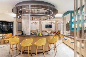 a restaurant with a bar with yellow stools at Hotel Gwalior Regency, a member of Radisson Individuals in Gwalior