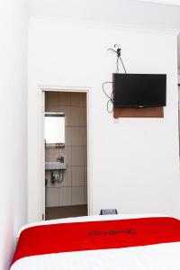 a room with a bed with a television and a bathroom at L'cost Homestay in Sawah
