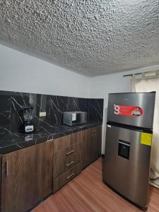 a kitchen with a stainless steel refrigerator and a counter at Rincón del Descanso in Loja