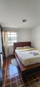 a bedroom with a bed with a wooden frame and a window at Rincón del Descanso in Loja
