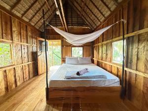 a bed in a wooden room with a hammock at Lily's Beach Bungalows in Koh Rong Island