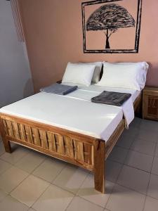 a large wooden bed in a room at Campement les Baobabs Abene in Abémé