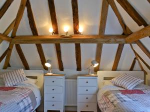 two beds in a room with wooden beams at Fig Cottage in Brabourne +6 photos