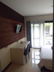 a hotel room with a bed and a desk with a television at NEW KUBU DI BUKIT apartemen & motor bike rental in Jimbaran