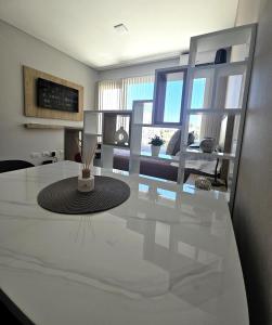 a white kitchen with a table and a living room at Tower Suites - Exclusiva Suite 9 - Centro de Neuquén in Neuquén