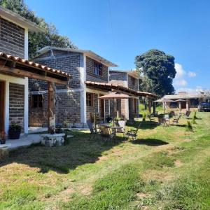 a house with chairs and tables in the yard at Altépetl Cabañas Zacatlán in Tomatlán