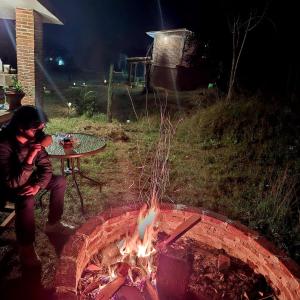 a woman sitting next to a fire pit at night at Altépetl Cabañas Zacatlán in Tomatlán