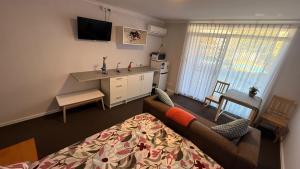 a living room with a bed and a couch and a desk at Mandurah Coastal Studio - Pool Outlook in Mandurah
