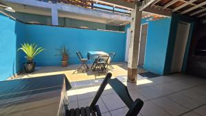 a patio with a table and chairs on a blue wall at Almar Hospedagem 2 ARRAIAL DO CABO in Arraial do Cabo