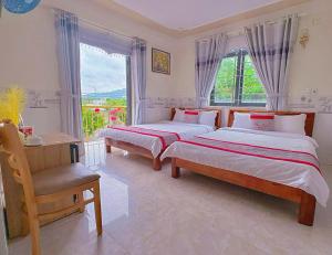 a bedroom with two beds and a chair and a window at KHÁCH SẠN HƯNG THỊNH - Gần biển, gần cảng khách - Trung tâm Lý Sơn in Ly Son