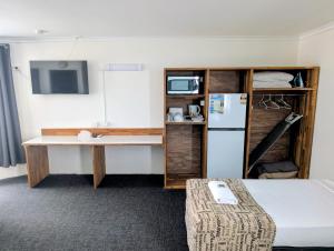 a room with a desk and a refrigerator at Hampton Villa Motel in Rockhampton