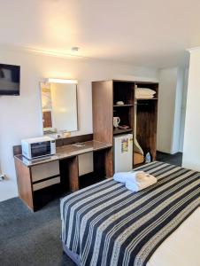 a hotel room with a bed and a desk at Hampton Villa Motel in Rockhampton