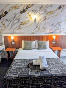 a bedroom with a large bed with two tables at Hampton Villa Motel in Rockhampton