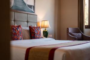 a hotel room with a bed and a lamp and a chair at 8fold by Larisa, Shimla in Shimla