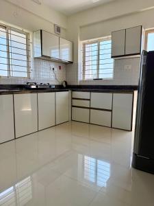 a large white kitchen with white cabinets and appliances at Between Tides nd Toasts Udupi Manipal in Manipal