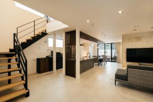 a kitchen and a living room with a staircase in a house at MIRATIO Umui Sauna&Spa in Onna